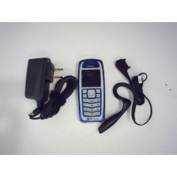 Мобильный телефон Nokia 3100 2003 года выпуска, отличающийся характерным сине-белым дизайном в виде моноблока. В комплект входят аксессуары, такие как совместимое сетевое зарядное устройство и гарнитура. (в коробке)